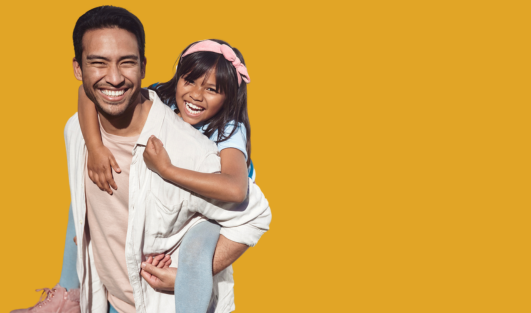 A man carrying a child on his back while smiling.