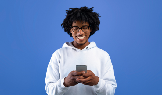 A man smiling and looking down at his phone that he is holding.