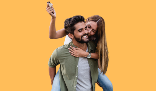 A  woman on a man's back kissing his cheek while holding a set of keys.