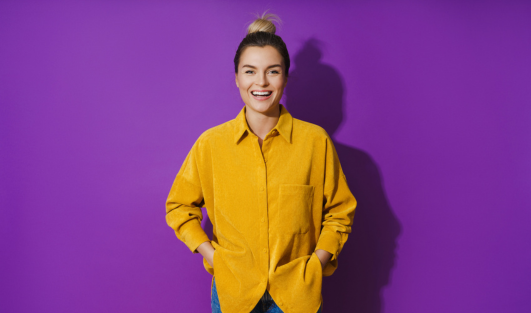 A woman smiling with her hands in her pockets.