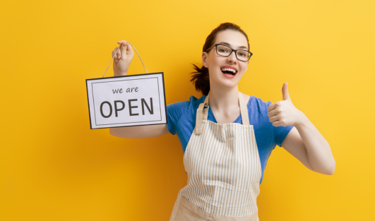 A woman wearing an apron, holding a sign that says, 