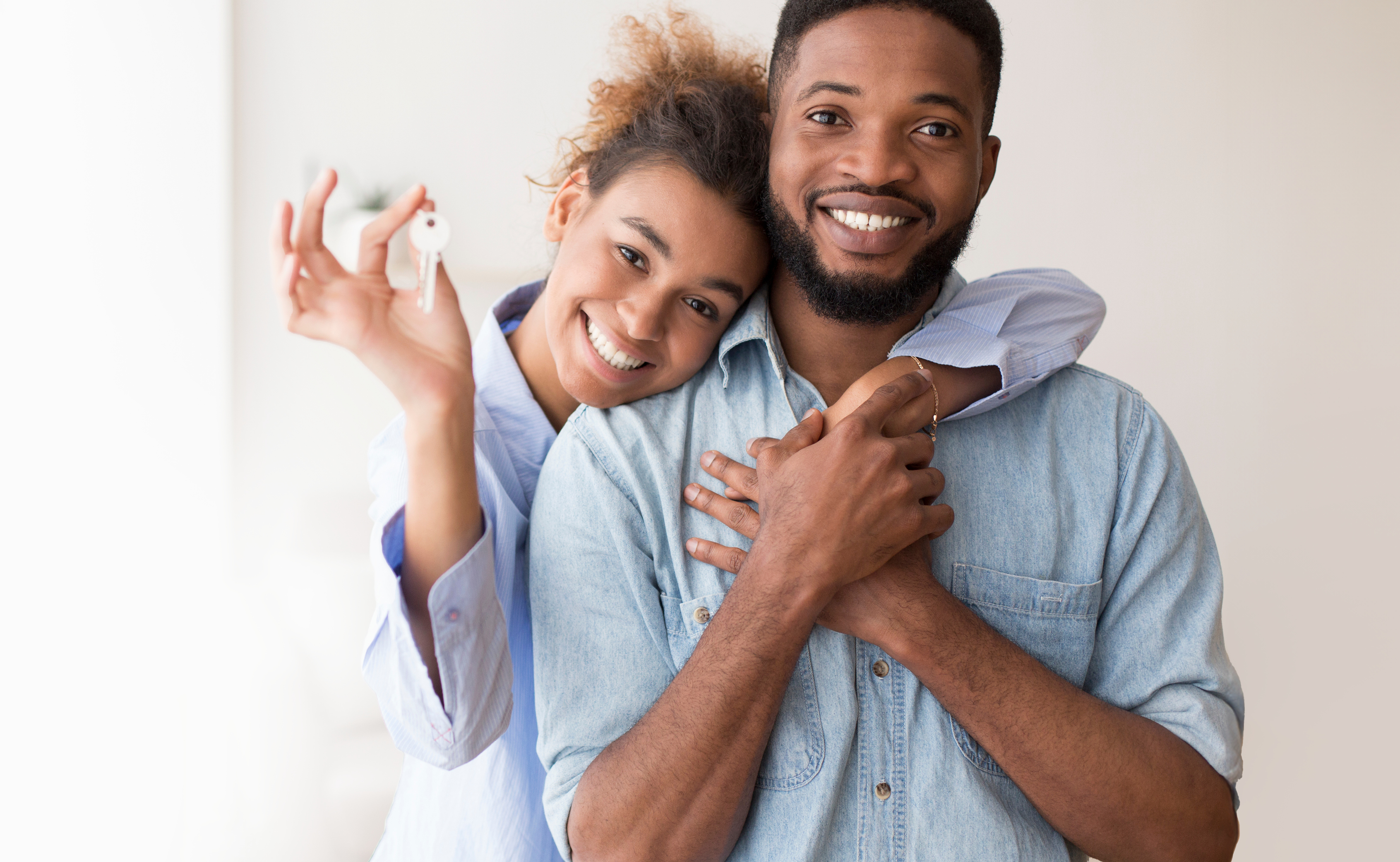 A man and woman hugging while holding a key