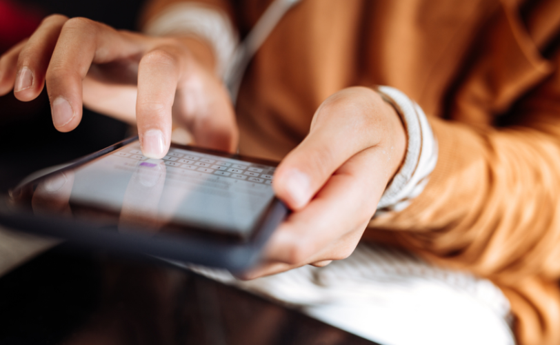 A person's hands typing on a mobile device.