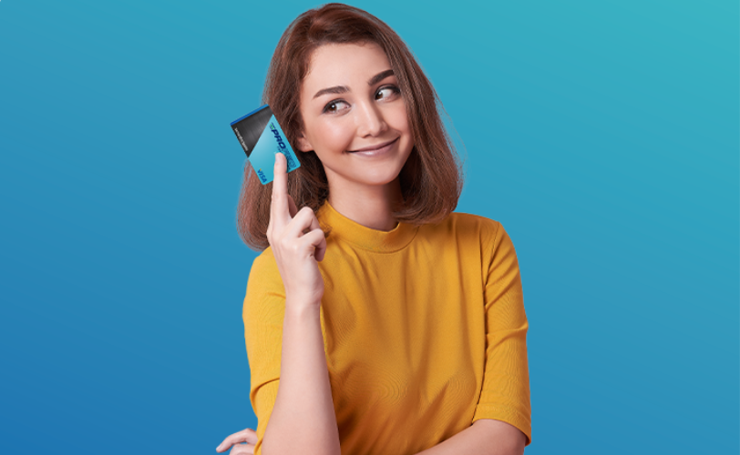 A woman holding a credit card and smiling while looking at it.