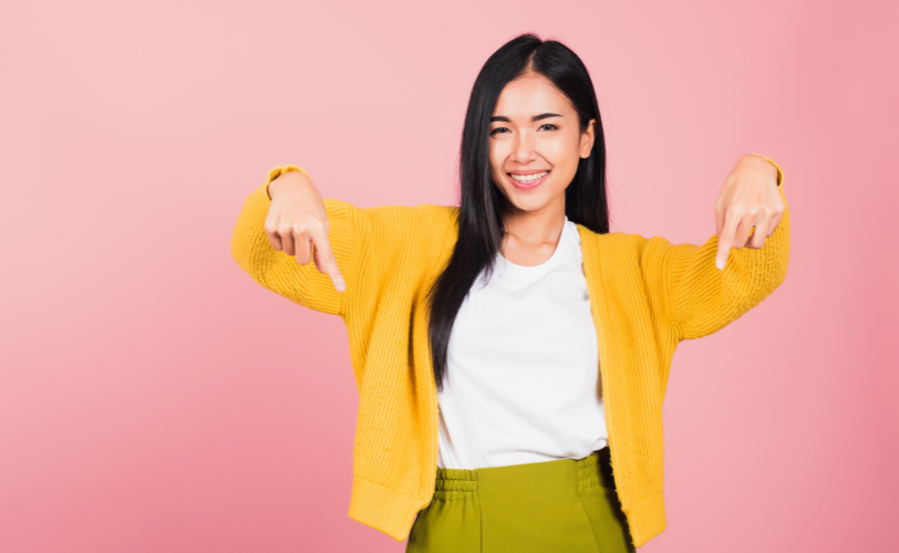 A woman smiling and pointing down.