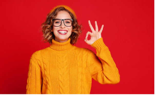 A woman smiling and holding up the ok symbol with her hand.