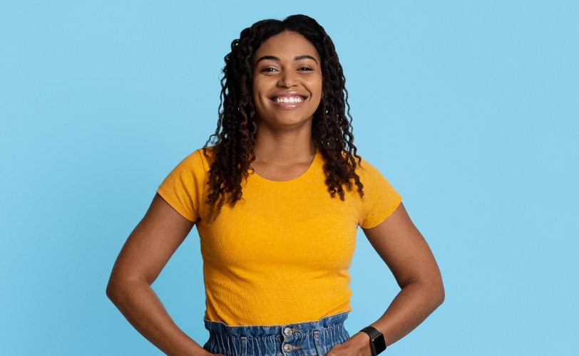 A woman smiling with her hands in her pockets.