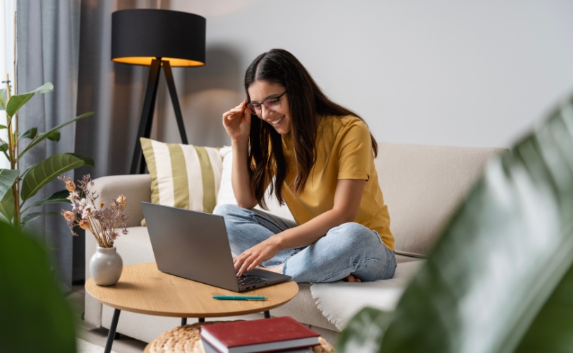 A woman sitting on a couch in a living room looking at a laptop.