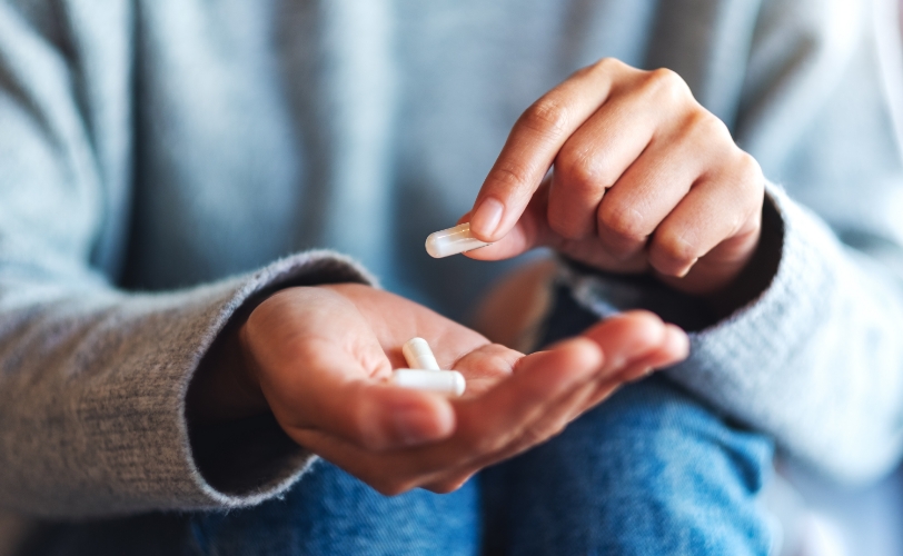 A woman holding pills in her hand.