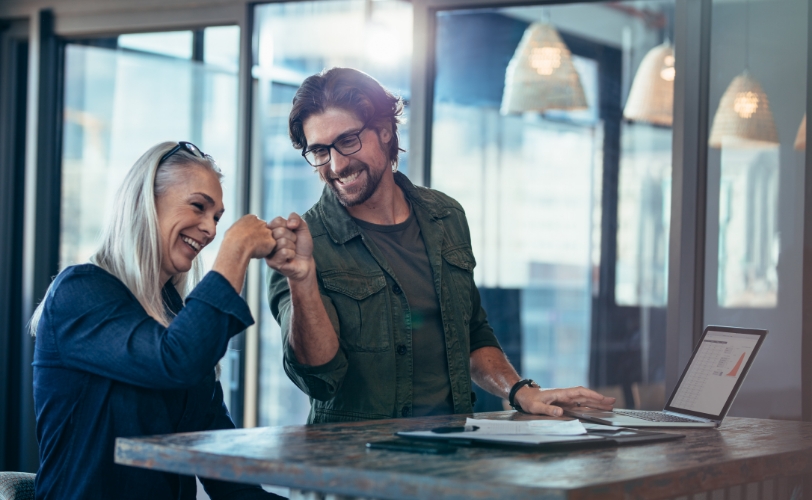 A man and woman smiling and giving each other a fist pump.