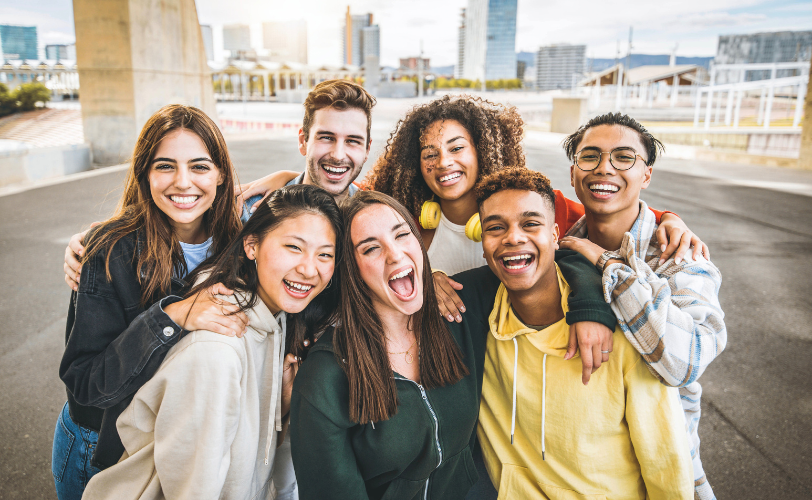 A group of people smiling huddled together outside.