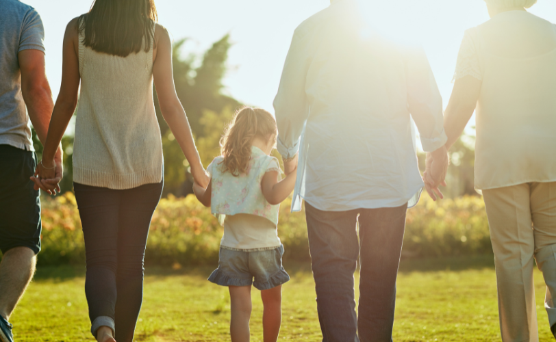 A family in a line holding hands and walking outside.