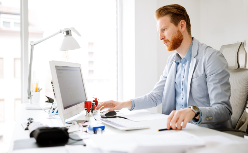 A man sitting at a business desk intently looking a computer screen.