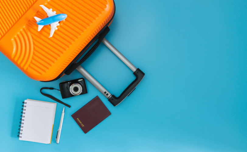 A suitcase, toy airplane, camera, passport, pen and notebook.