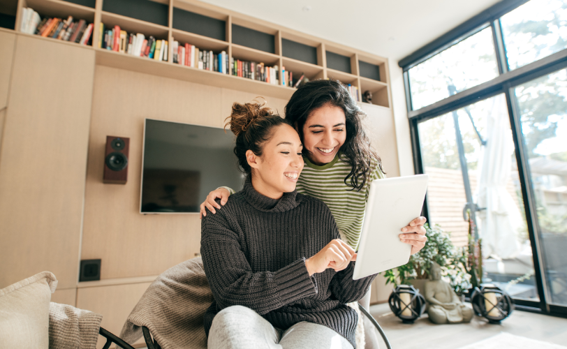 Two women looking at a tablet together in a house.