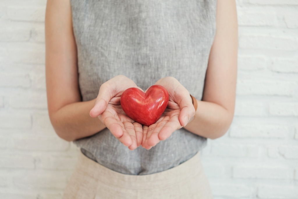 A lady holding a red heart in her hands.