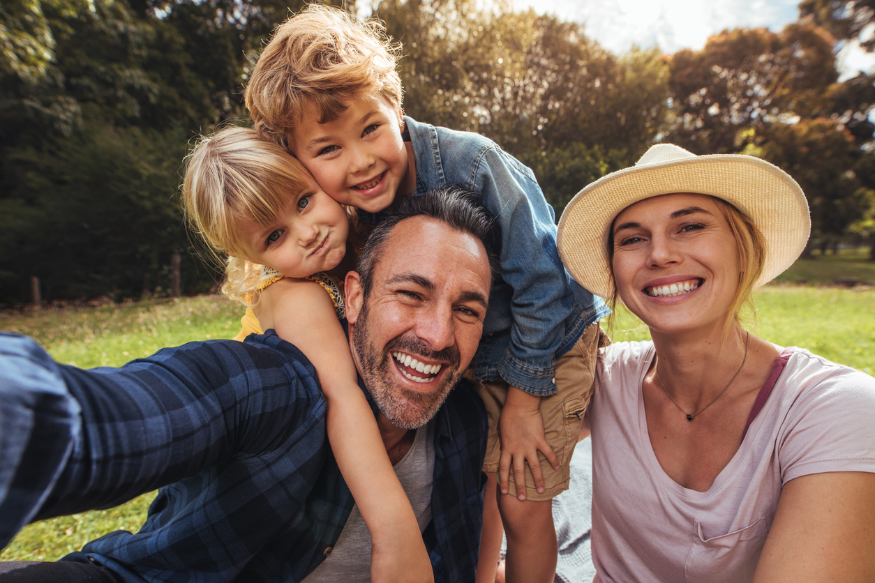 A happy family sitting outside taking a selfie.