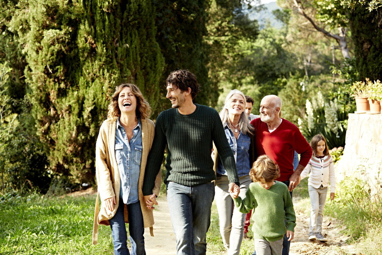 A family smiling and walking outside.