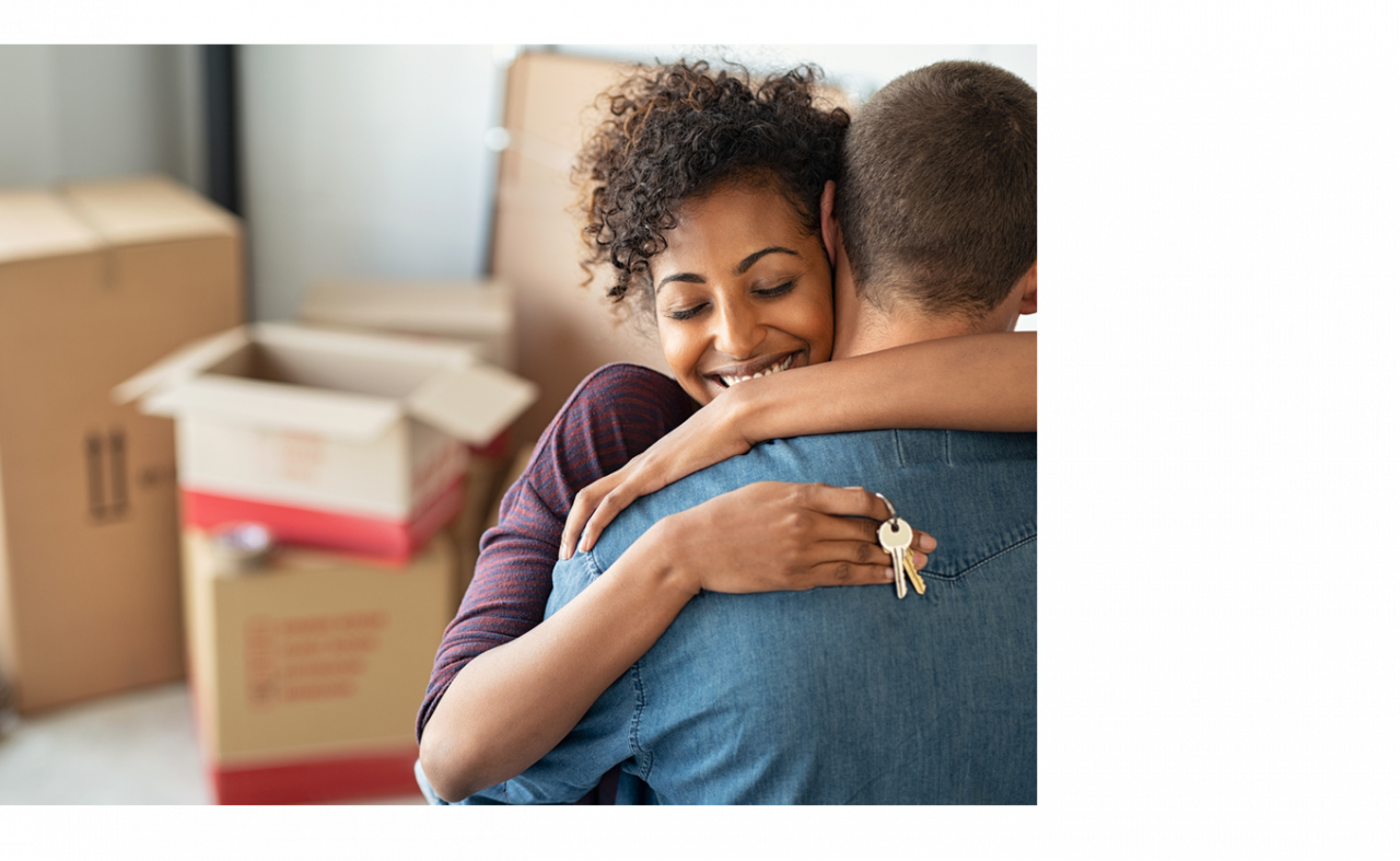 A cropped photo of a woman hugging a man and holding keys in their new house.