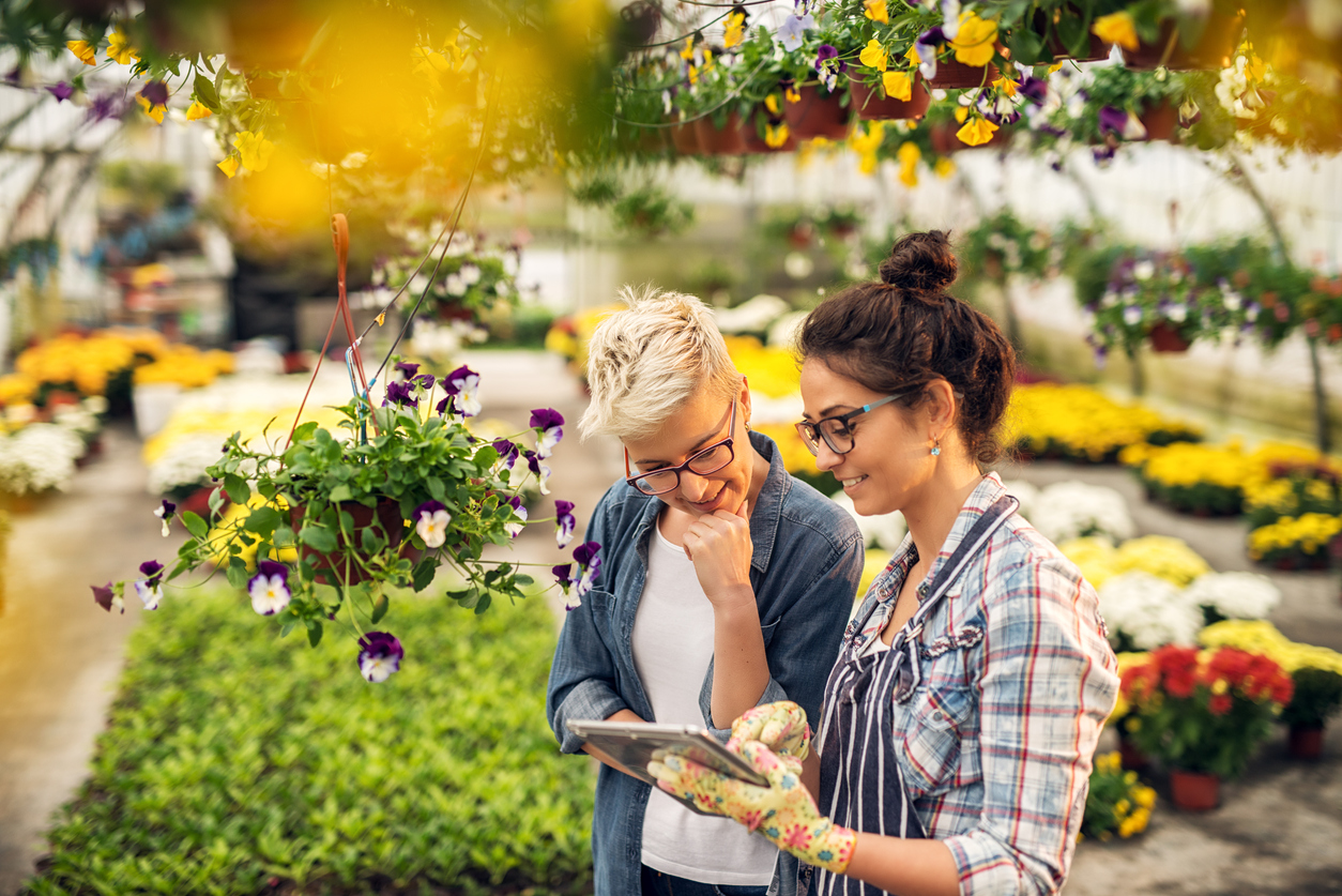 Florist woman showing a list of flowers on a tablet to a customer.