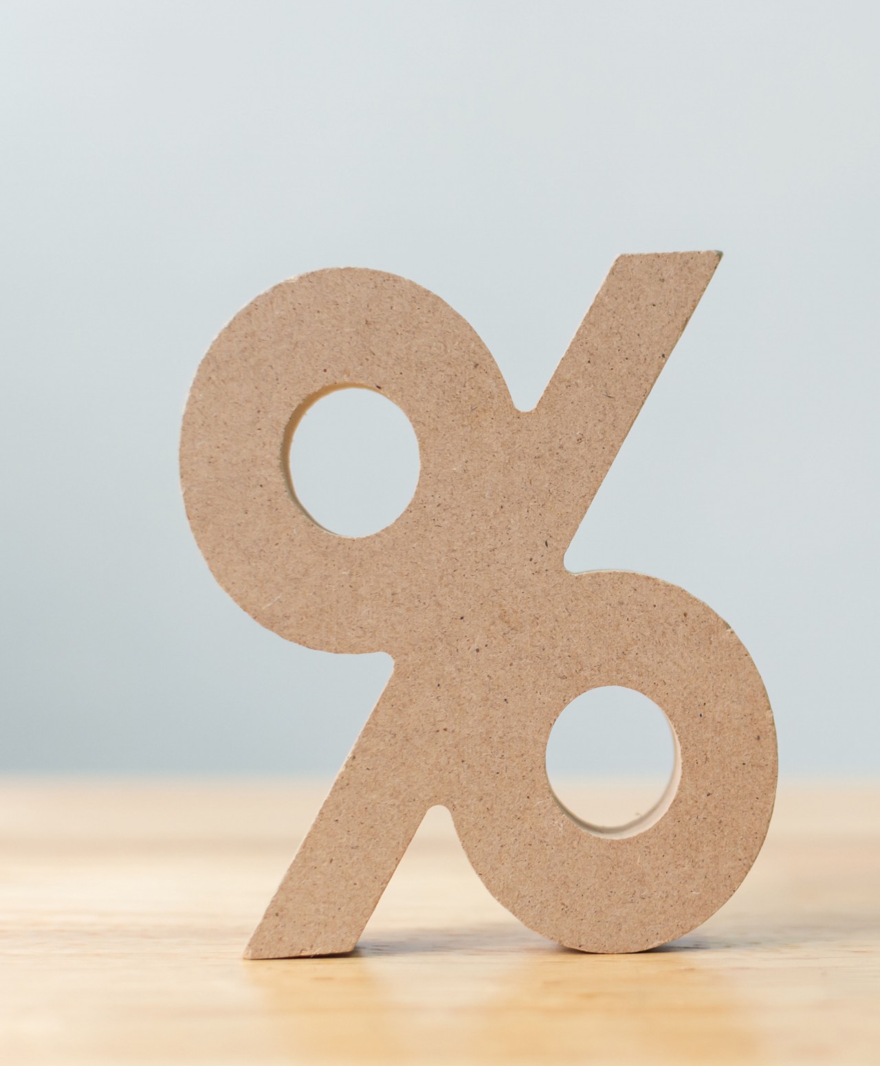 A wooden percentage sign symbol sitting on top of a desk.