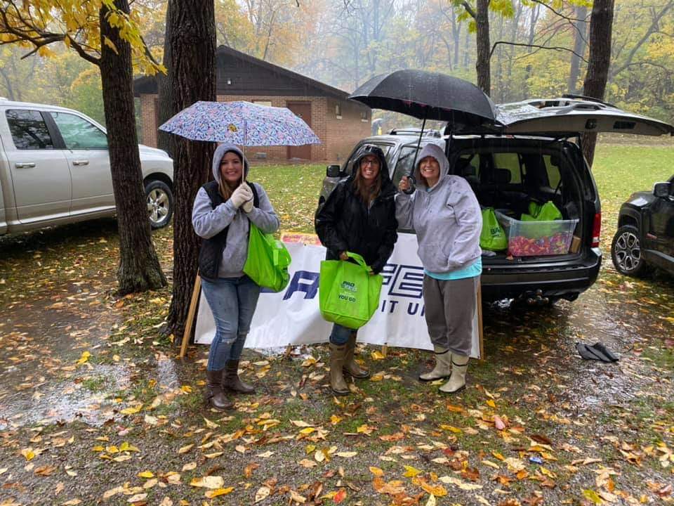 ProFed staff with umbrellas passing out candy at a Halloween event.