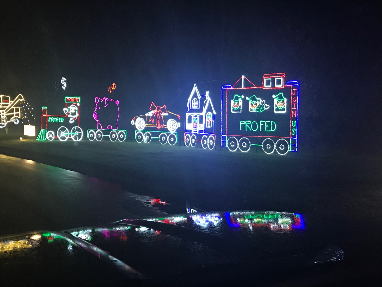 A train display of lights in a park lit up at night.