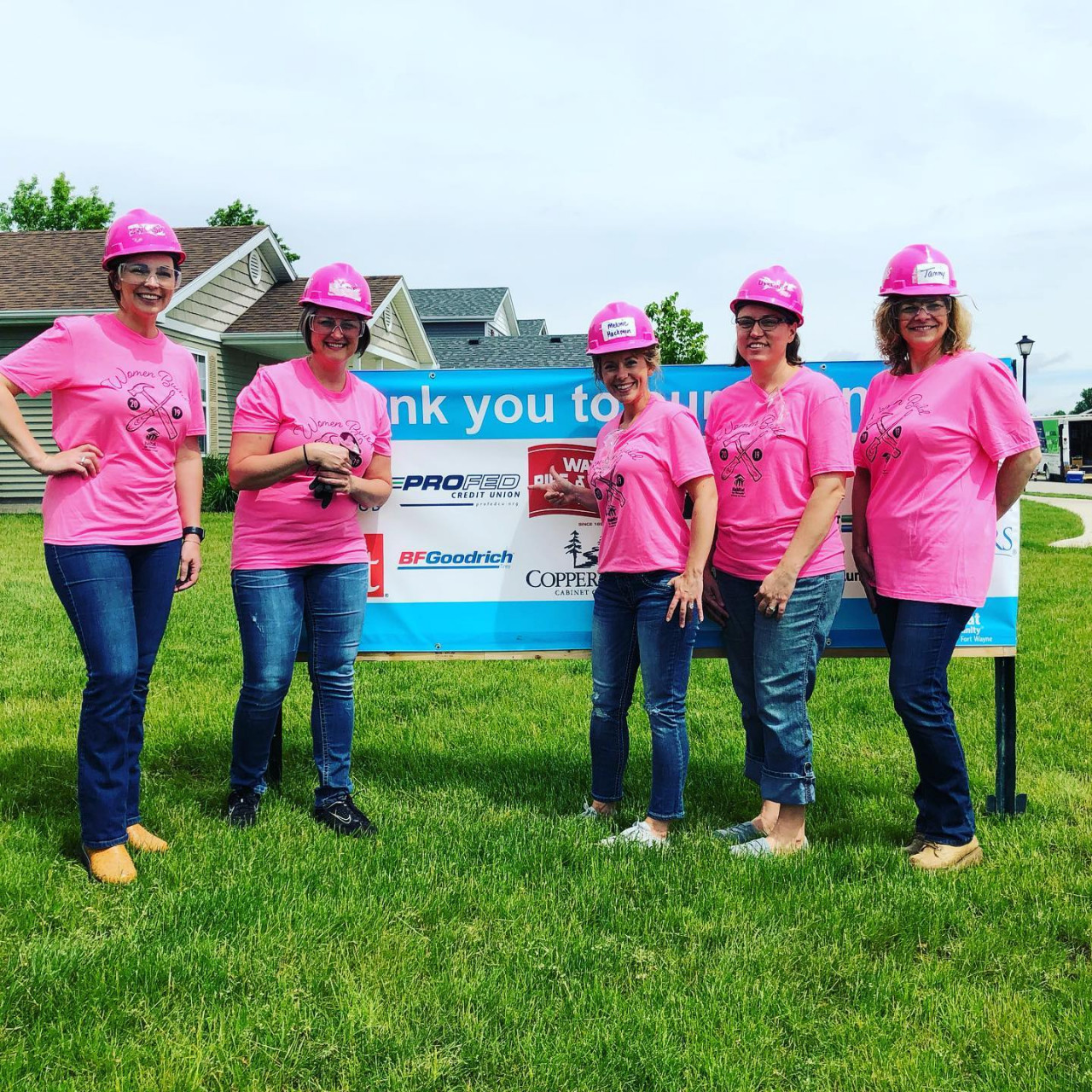 Group of women in pink shirts and hard hats.