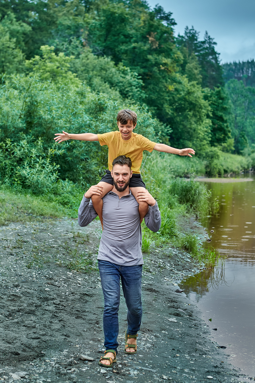 A cheerful father and son walking near the river.