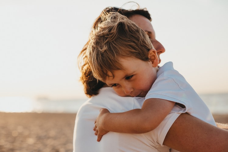 A woman hugging a child outside.