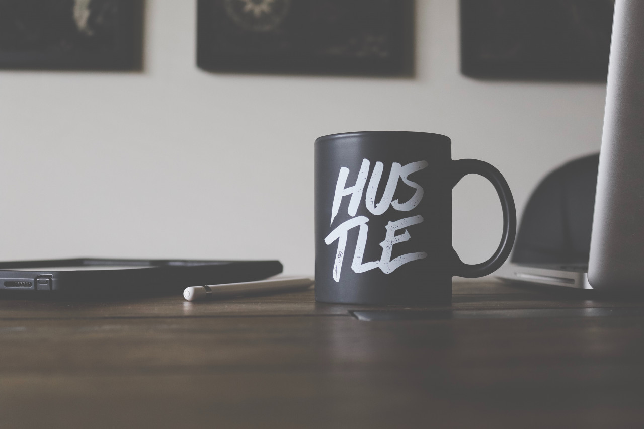 A coffee cup sitting on a table next to a laptop.