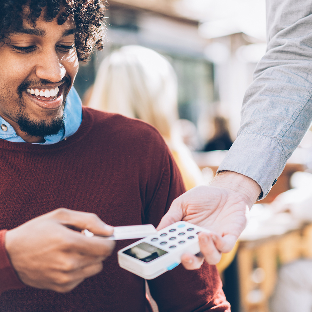 Young man swiping his credit card at a restaurant.