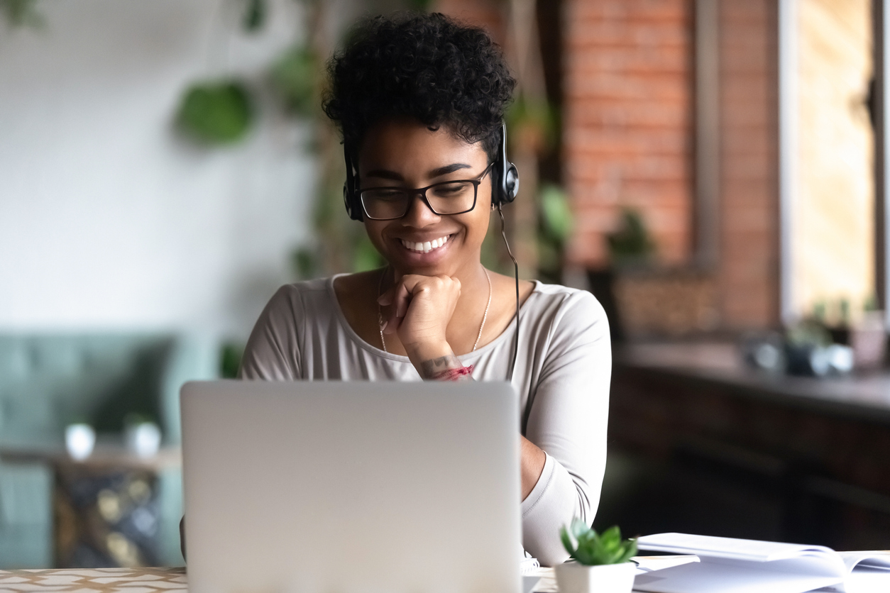A smart student using headphones and looking at her computer screen.