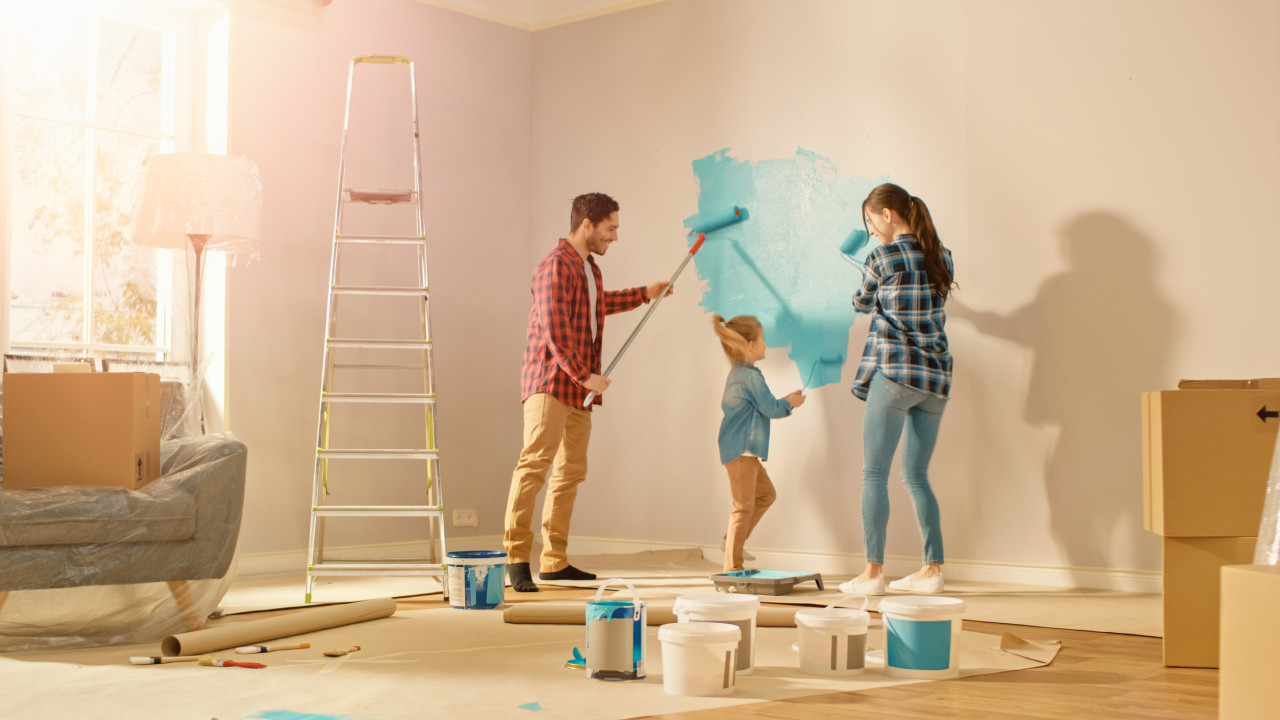 A man, woman, and child paint rolling a wall in their home.