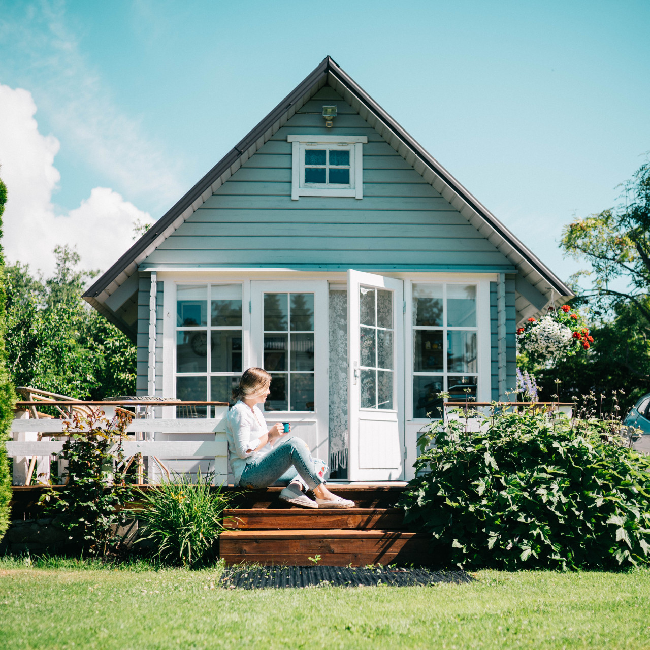 A woman sitting on the steps outside in front of a house.